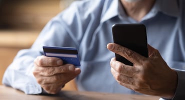 Elderly man holding a credit card and phone