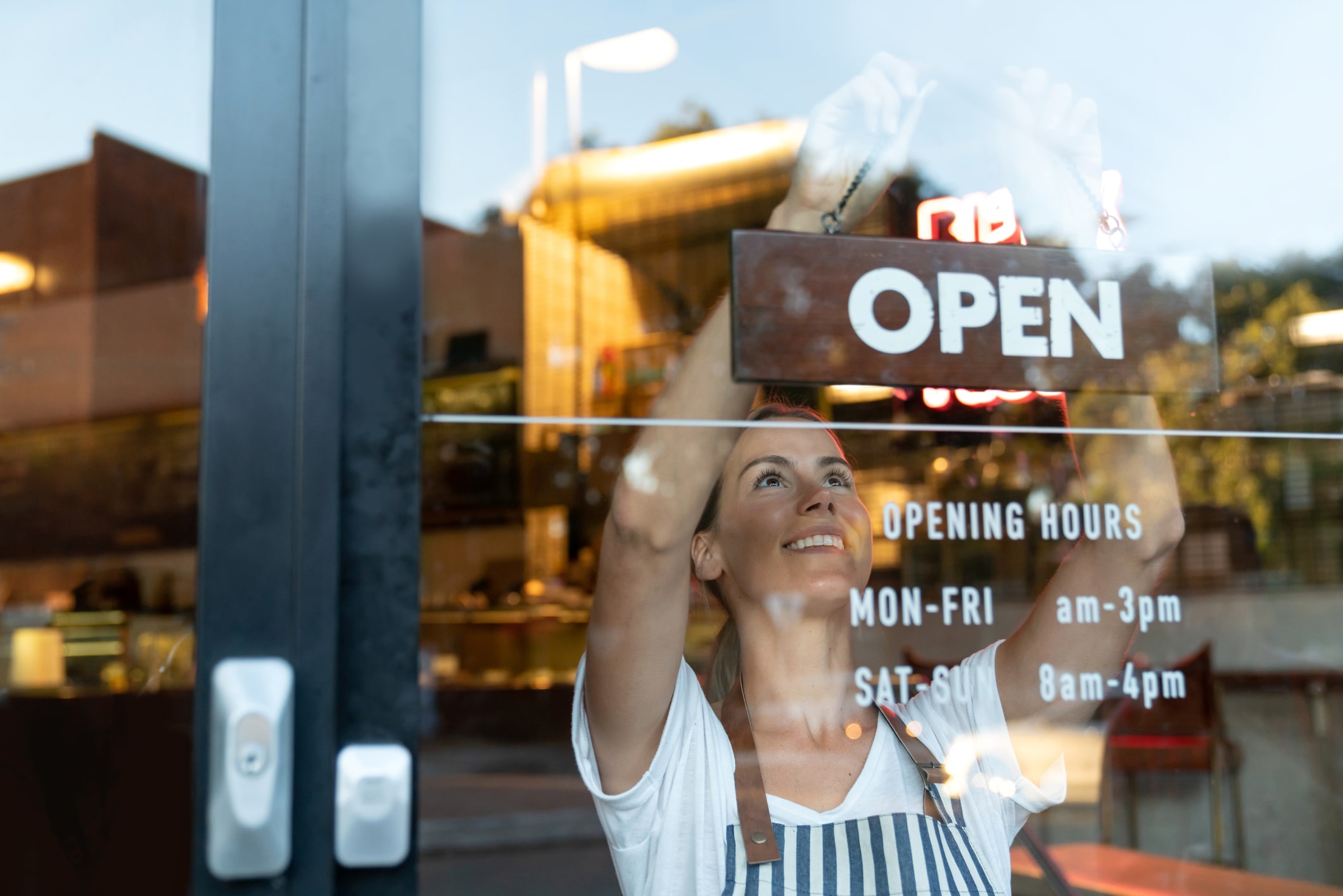 girl putting up a business open sign