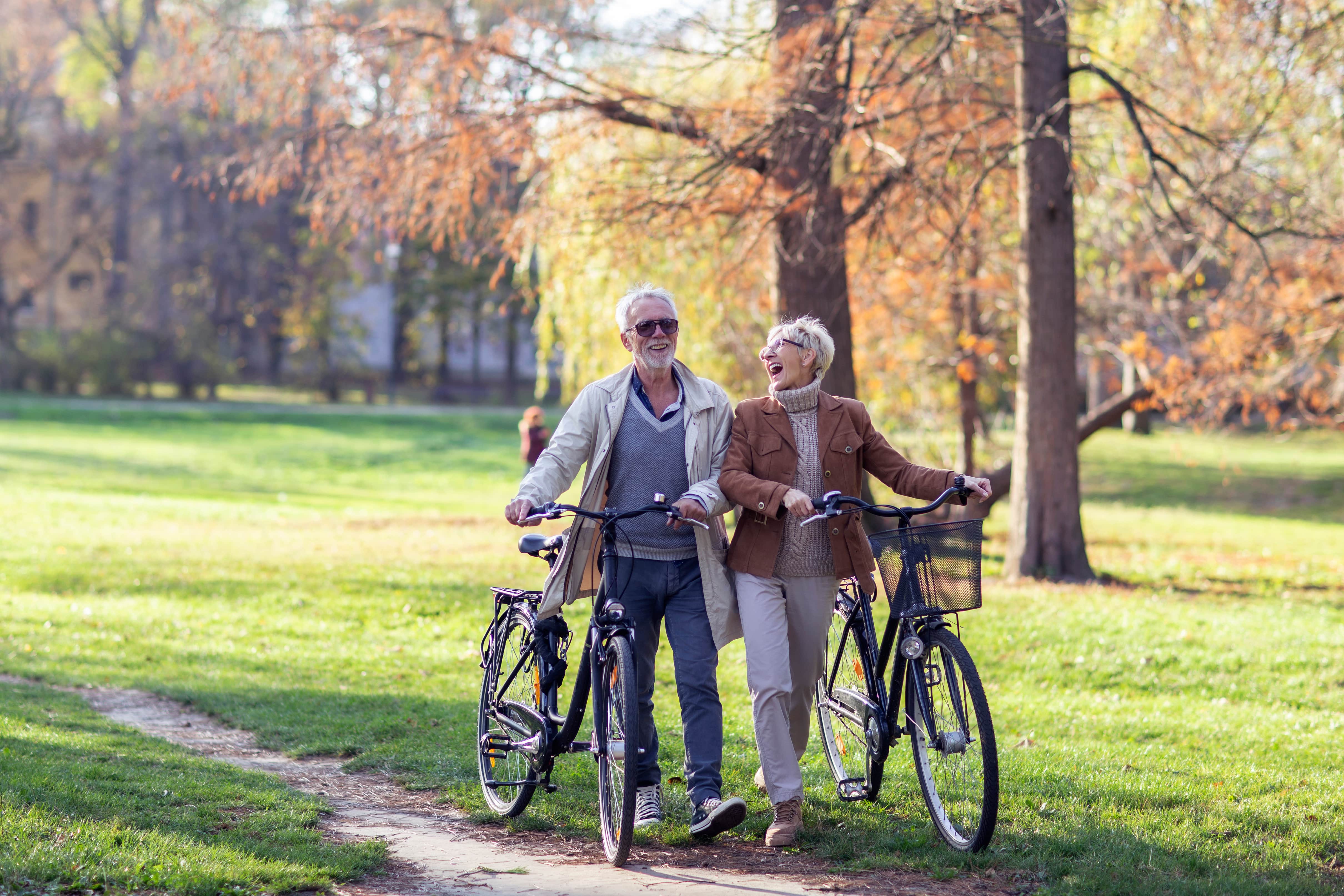 retired couple walking bikes