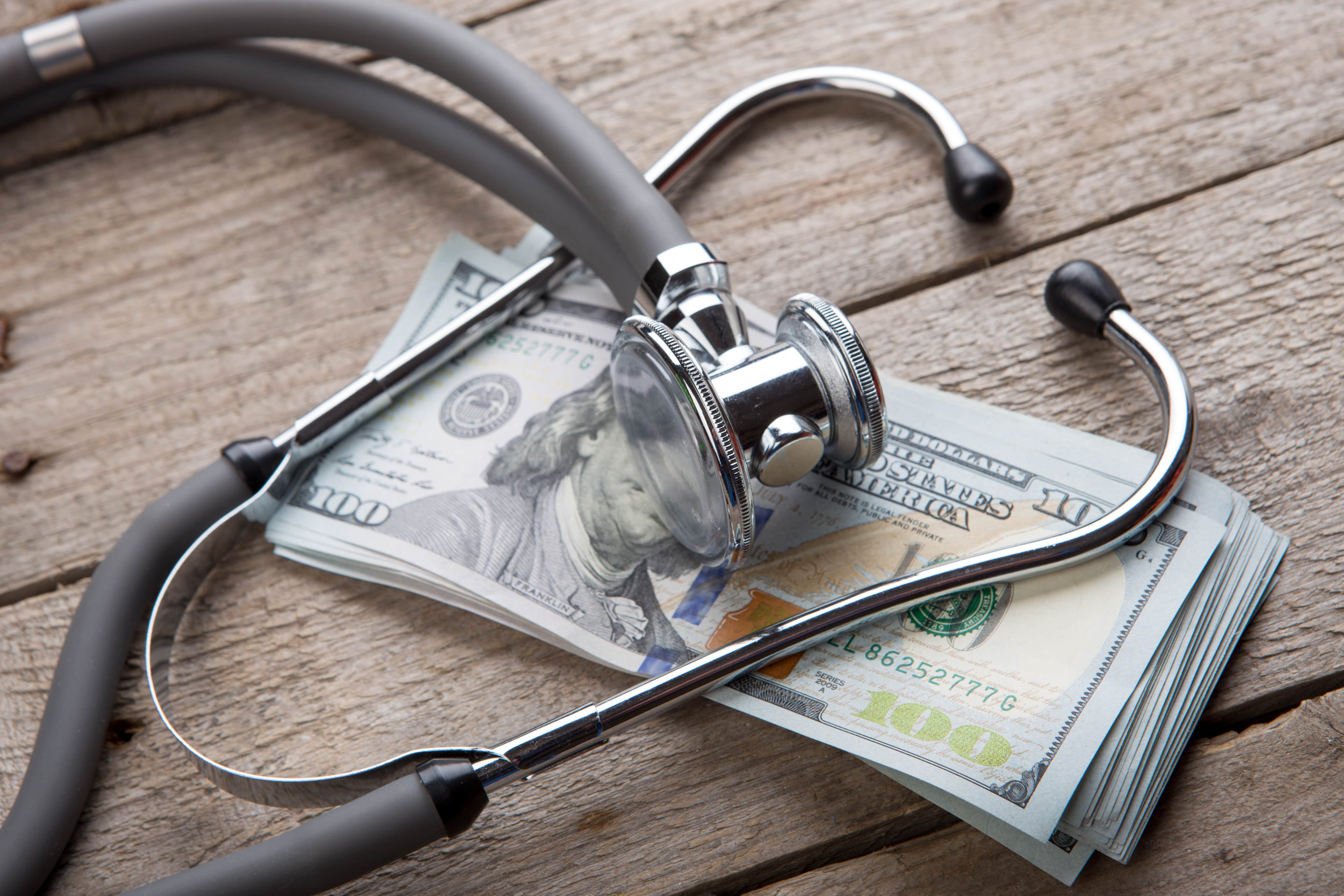 stethoscope over a stack of 100 dollar bills